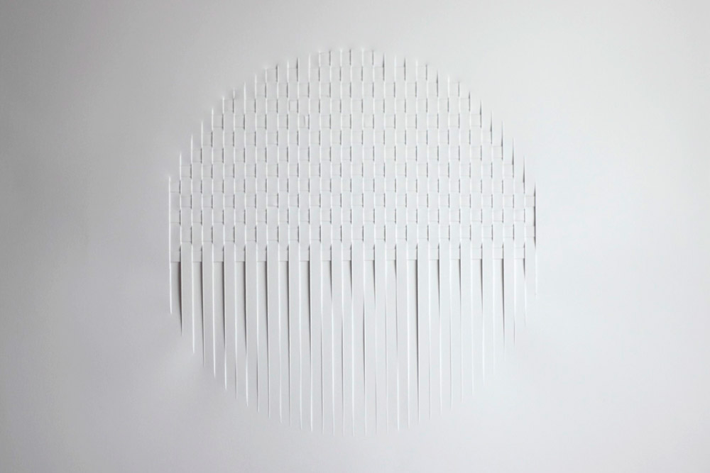 collage with white strips of paper woven into a a white paper background